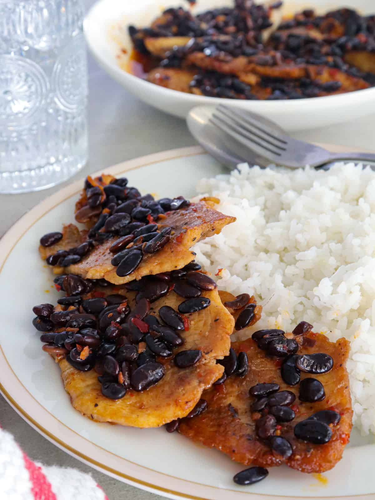 tilapia with black beans on a white plate with steamed rice.