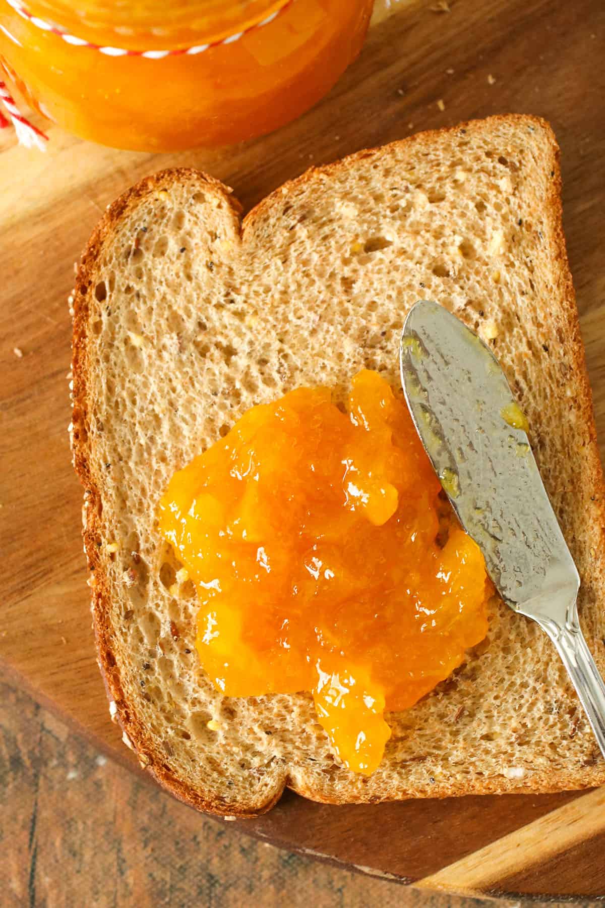 spreading mango jam on wheat toast.