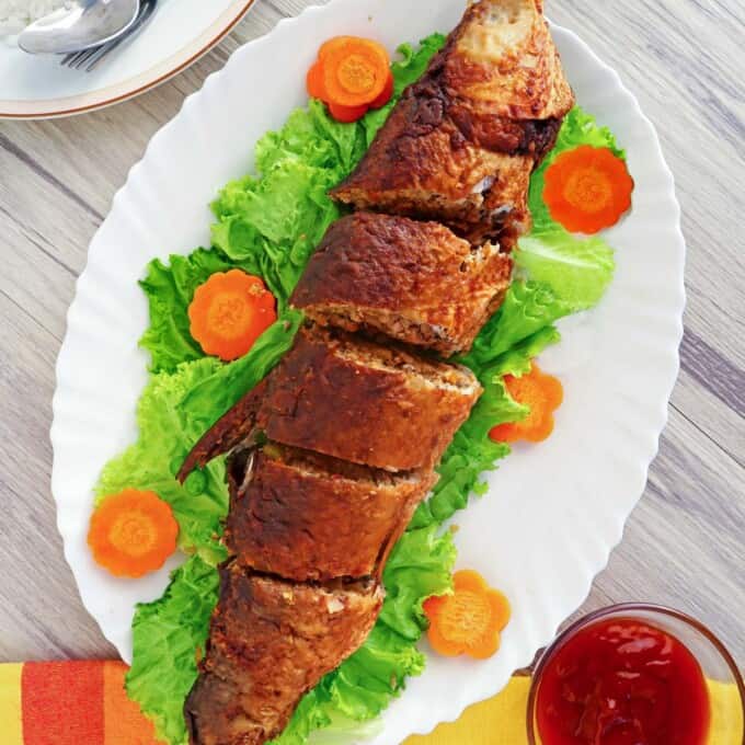 Relyenong Bangus on a white serving platter with carrot and lettuce garnish.