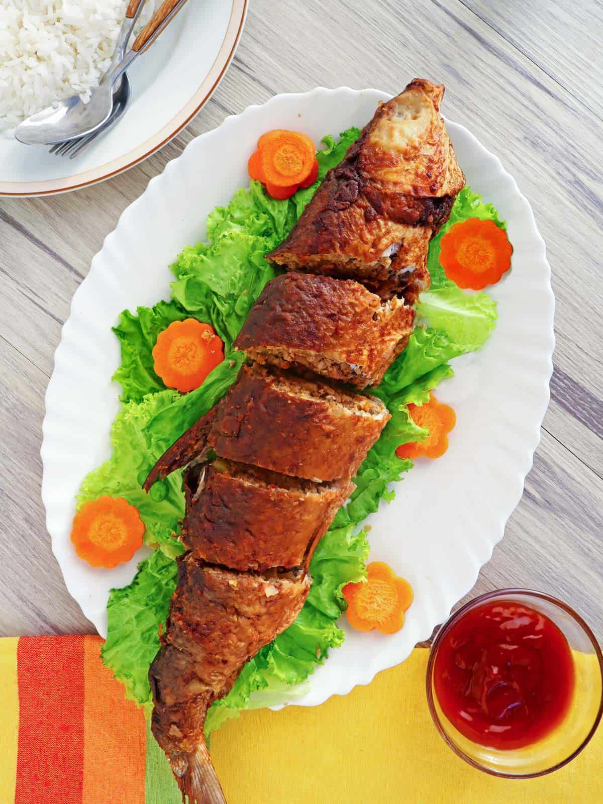 Relyenong Bangus on a white serving platter with carrot and lettuce garnish.