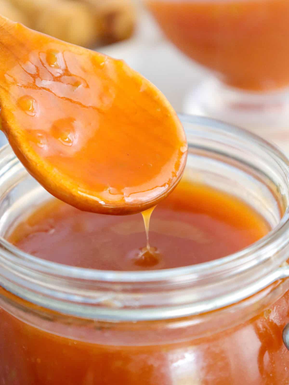 serving sweet and sour sauce with a wooden spoon from a jar.