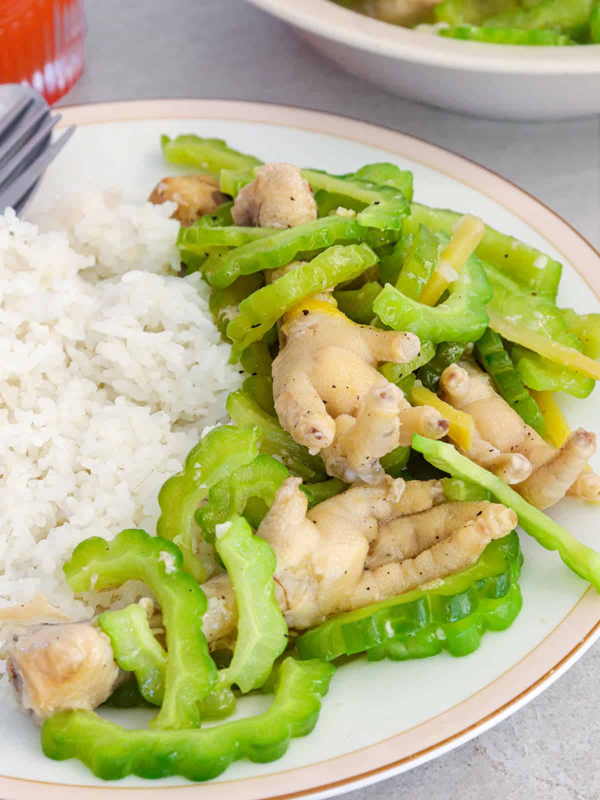 Ampalaya with Chicken Feet on a white plate with steamed rice.