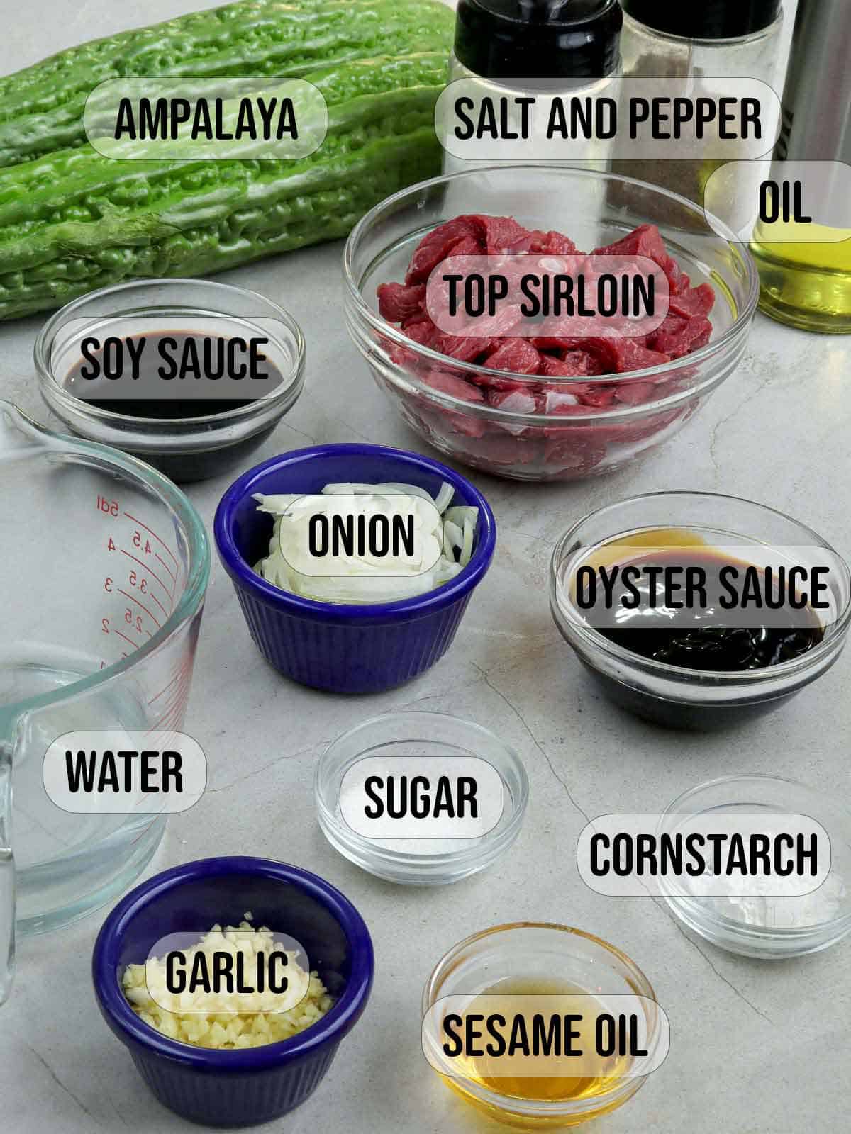 bittermelon, sirloin, onion, garlic, oyster sauce, cornstarch, sesame oil, water, soy sauce, sugar, salt, pepper, oil in bowls.