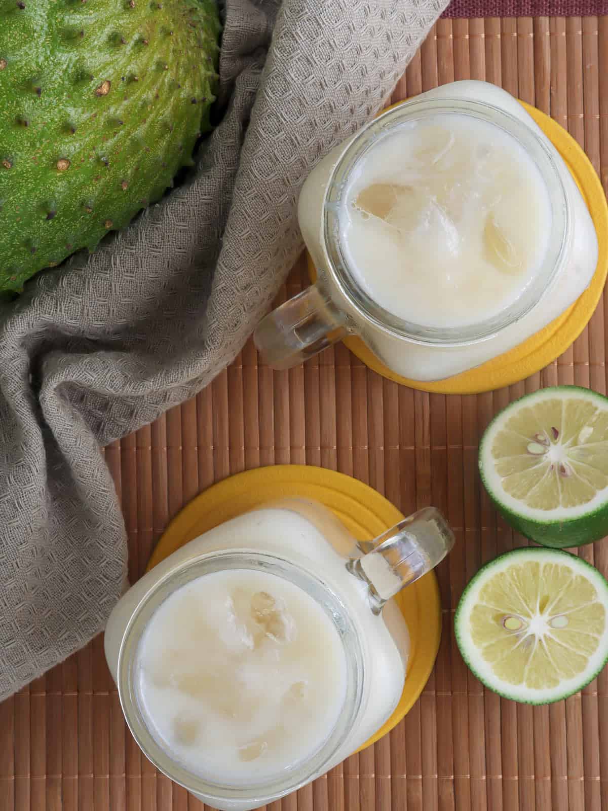 Guyabano Juice in glasses with sliced lime and guyabano fruit in the background.