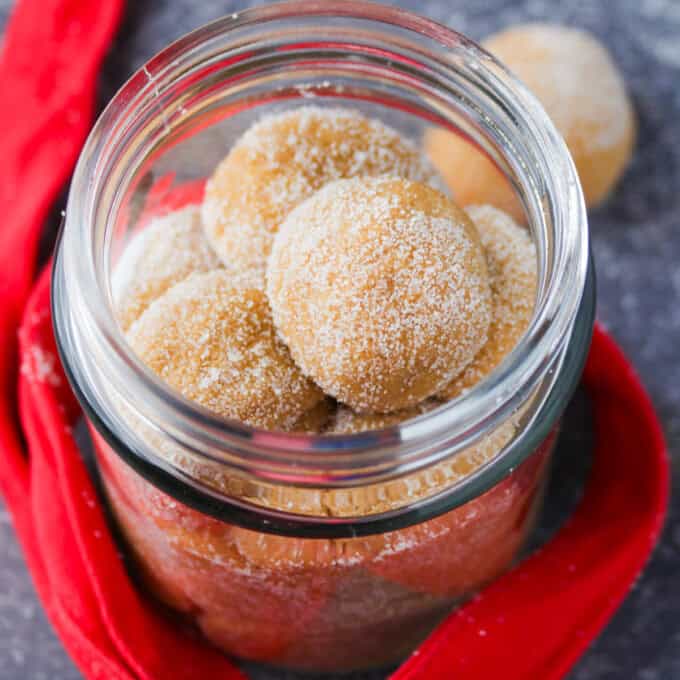 dulce de leche pastillas in a mason jar with red ribbon in the background.