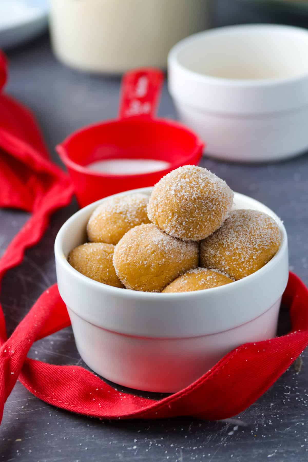 No-Cook Caramel Pastillas in a white bowl with a red ribbon and red measuring cup in the background.