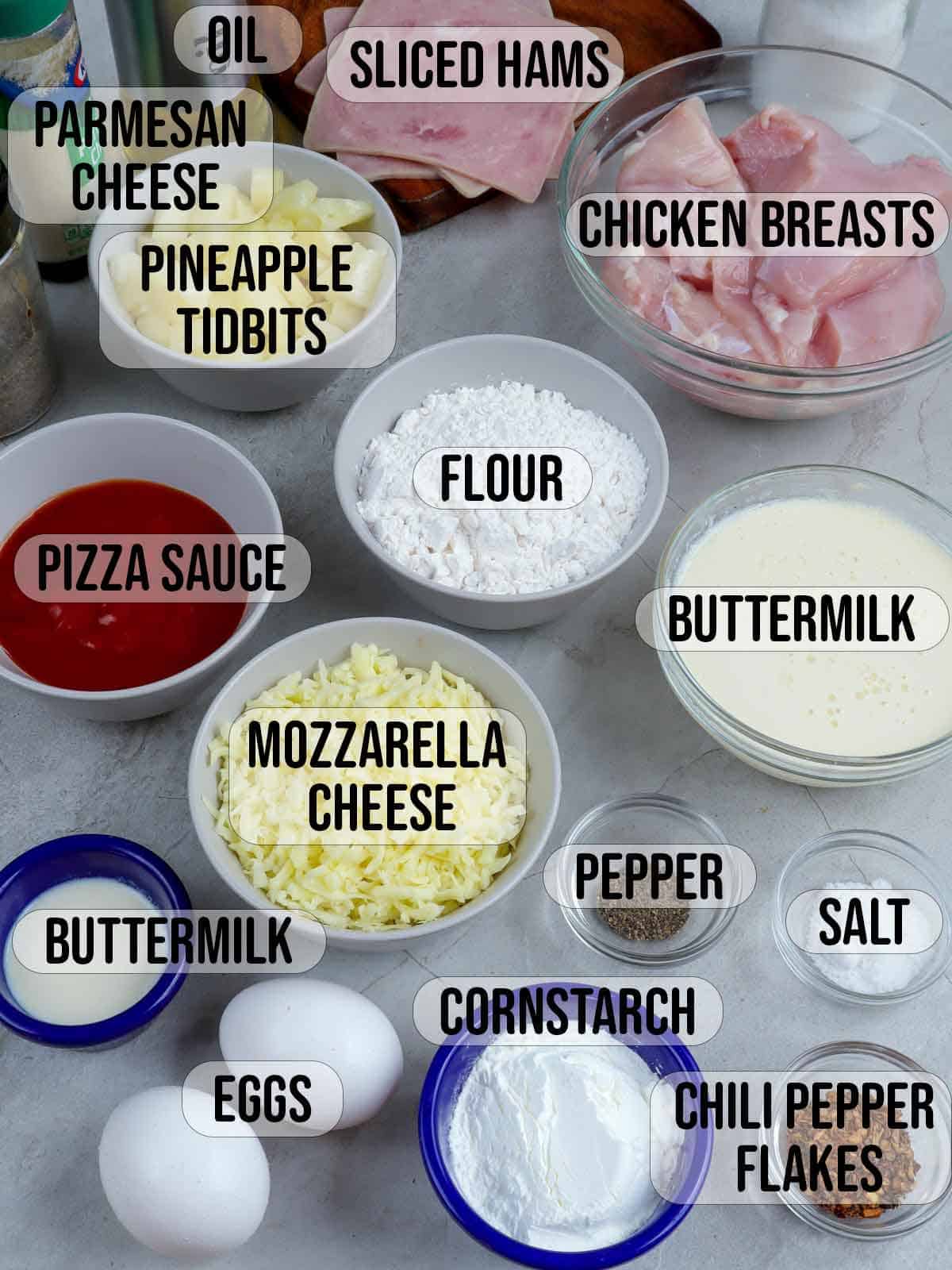 chicken breast, ham, pineapple, flour, eggs, cornstarch, buttermilk, salt, pepper, oil, garlic powder, dried chili flakes, mozzarella cheese, pizza sauce in bowls.