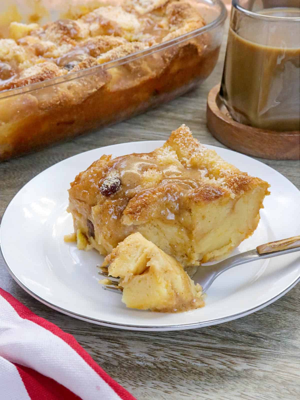 eating a slice of Hawaiian Bread Pudding on a white plate with a fork.