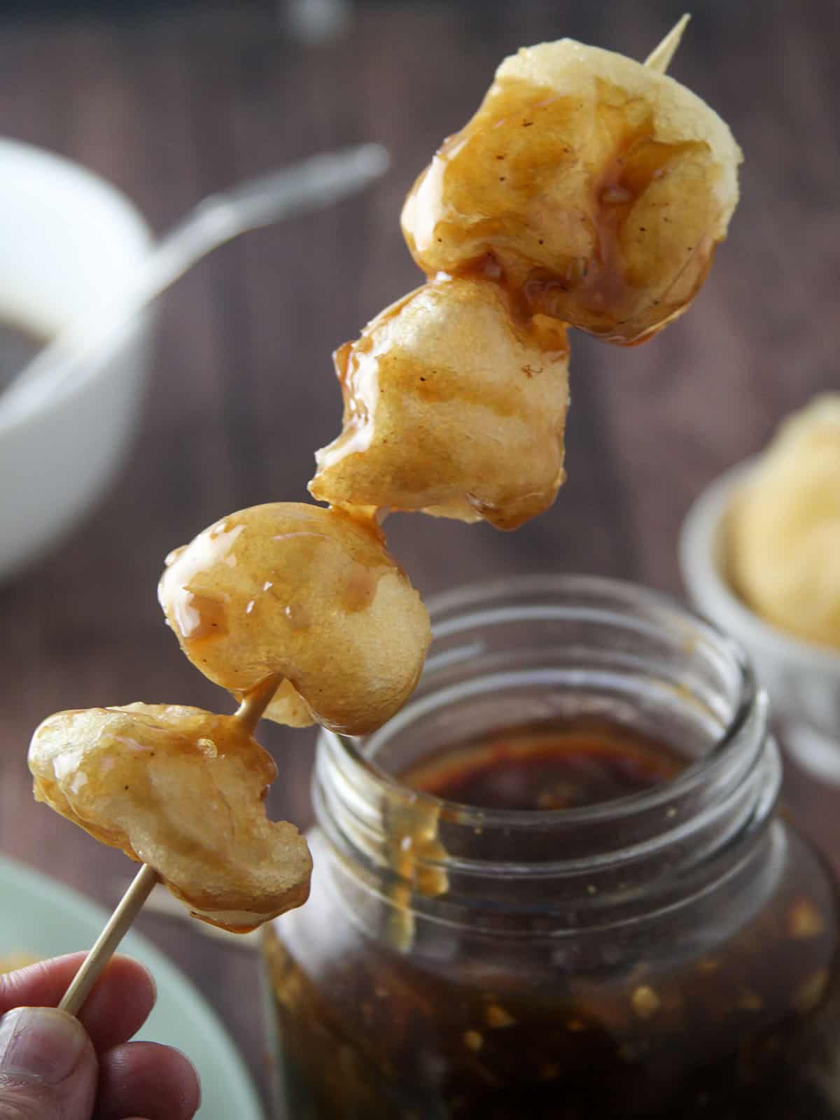 dipping fishball skewers in a jar of special fishball sauce.