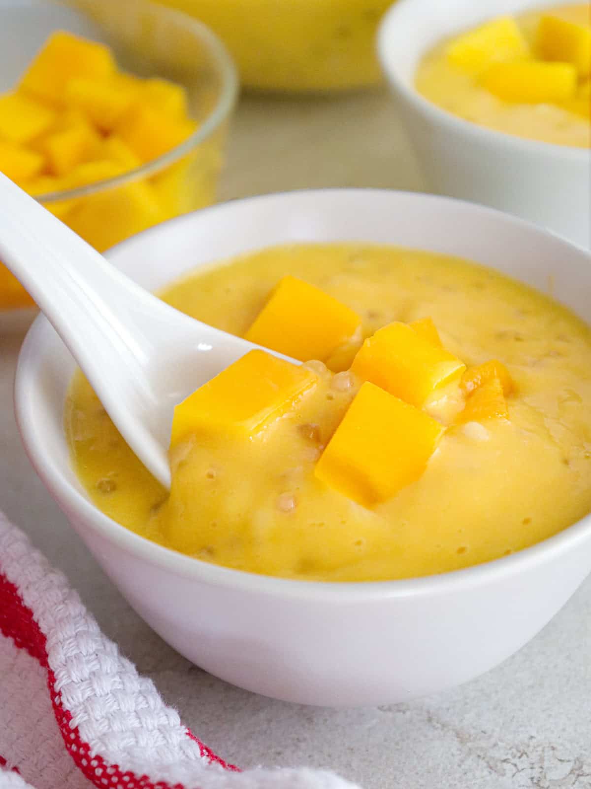 eating Mango Sago from a white bowl with a white soup spoon.