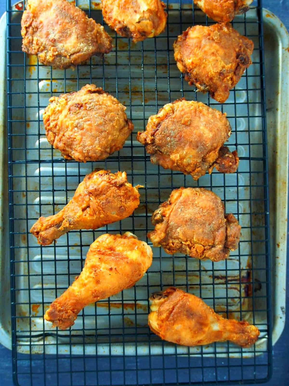 crispy fried chicken on a wire rack set over a baking sheet.