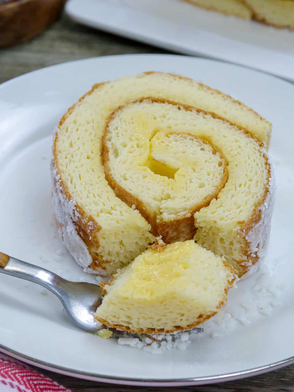 eating a slice of jelly roll cake on a white plate.