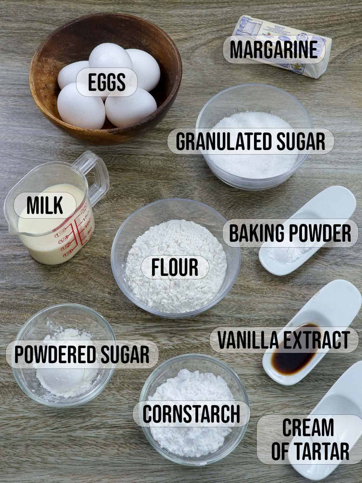 eggs, cream of tartar, flour, cornstarch, powdered sugar, sugar, vanilla extract, milk in bowls.