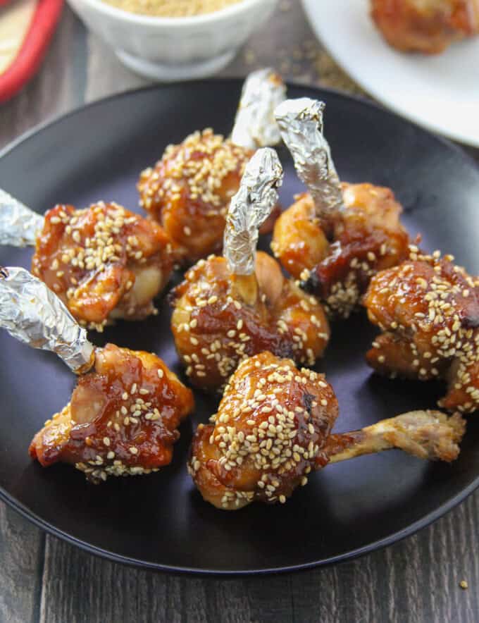 Plum Sauce Chicken Lollipops on a black plate.