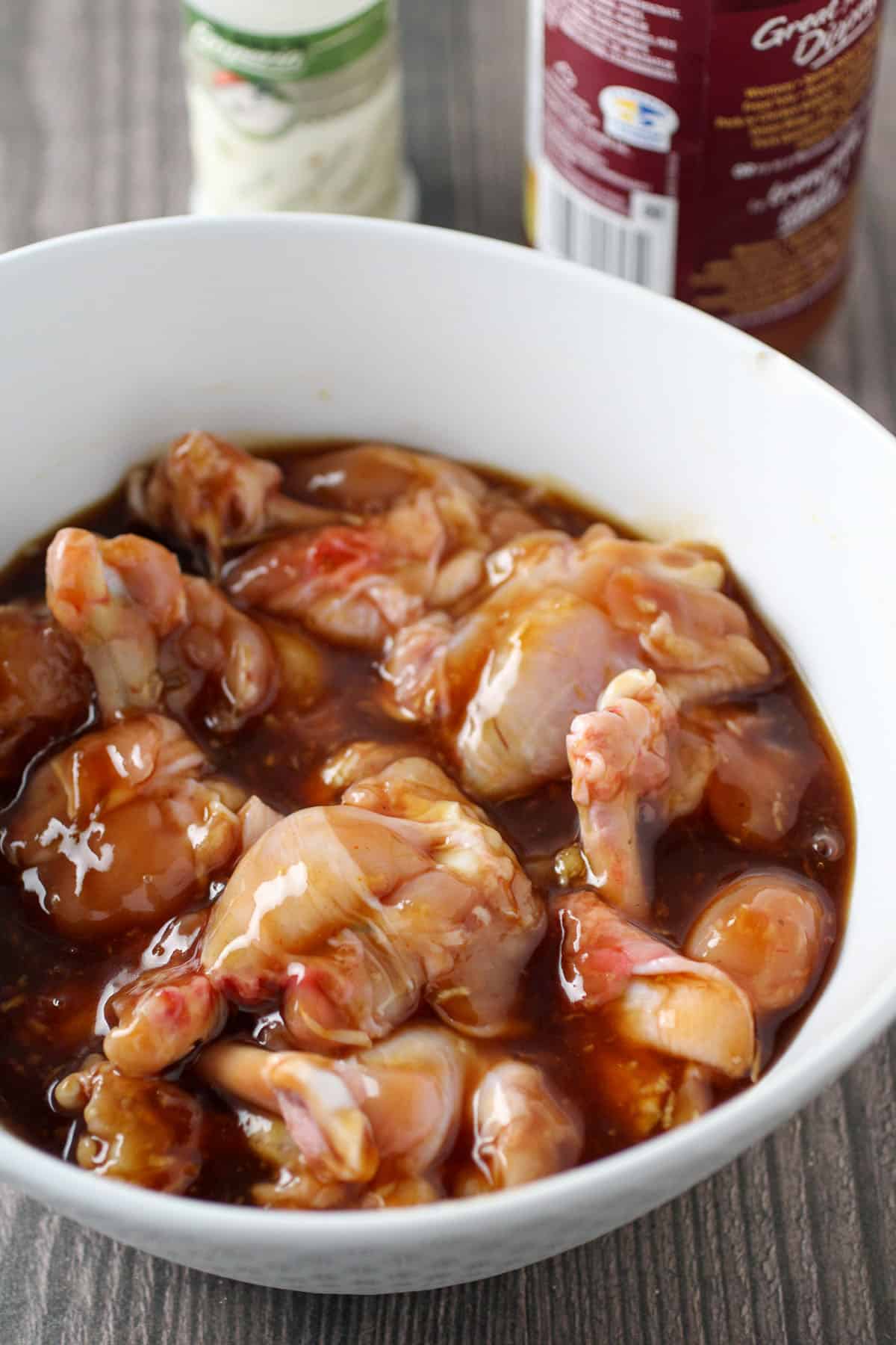 chicken wings marinating in a bowl with plum sauce mixture.