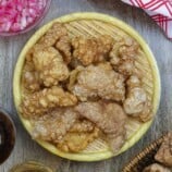 Pork Chicharon on a basket with a side of spicy vinegar.