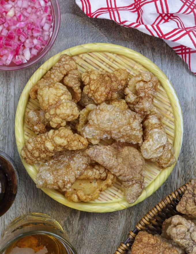 Pork Chicharon on a basket with a side of spicy vinegar.