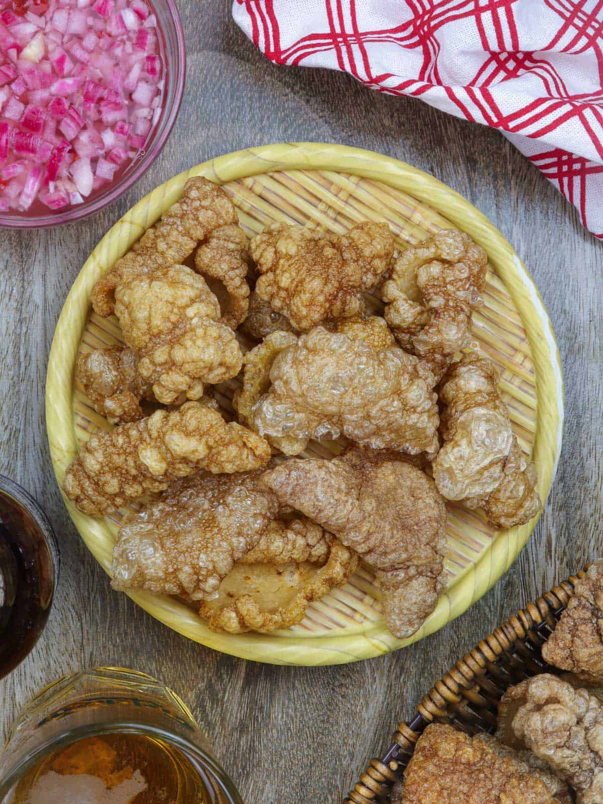 Pork Chicharon on a basket with a side of spicy vinegar.