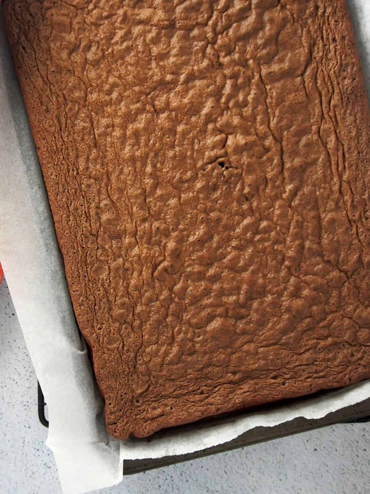 baked chocolate chiffon cake on a parchment-lined baking sheet.