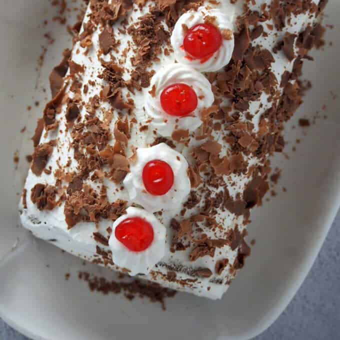 top view of a Black Forest Swiss Roll Cake on a white serving platter.