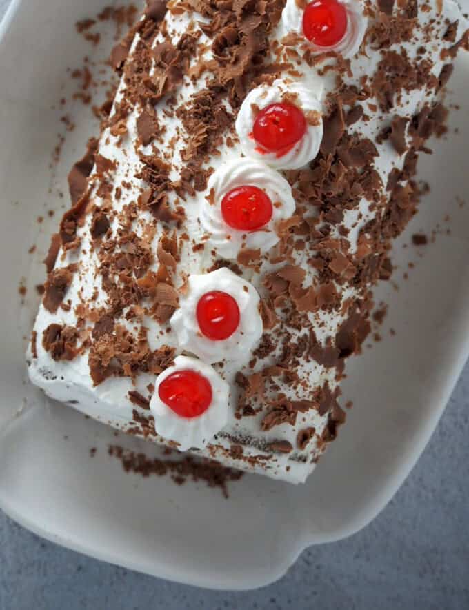 top view of a Black Forest Swiss Roll Cake on a white serving platter.