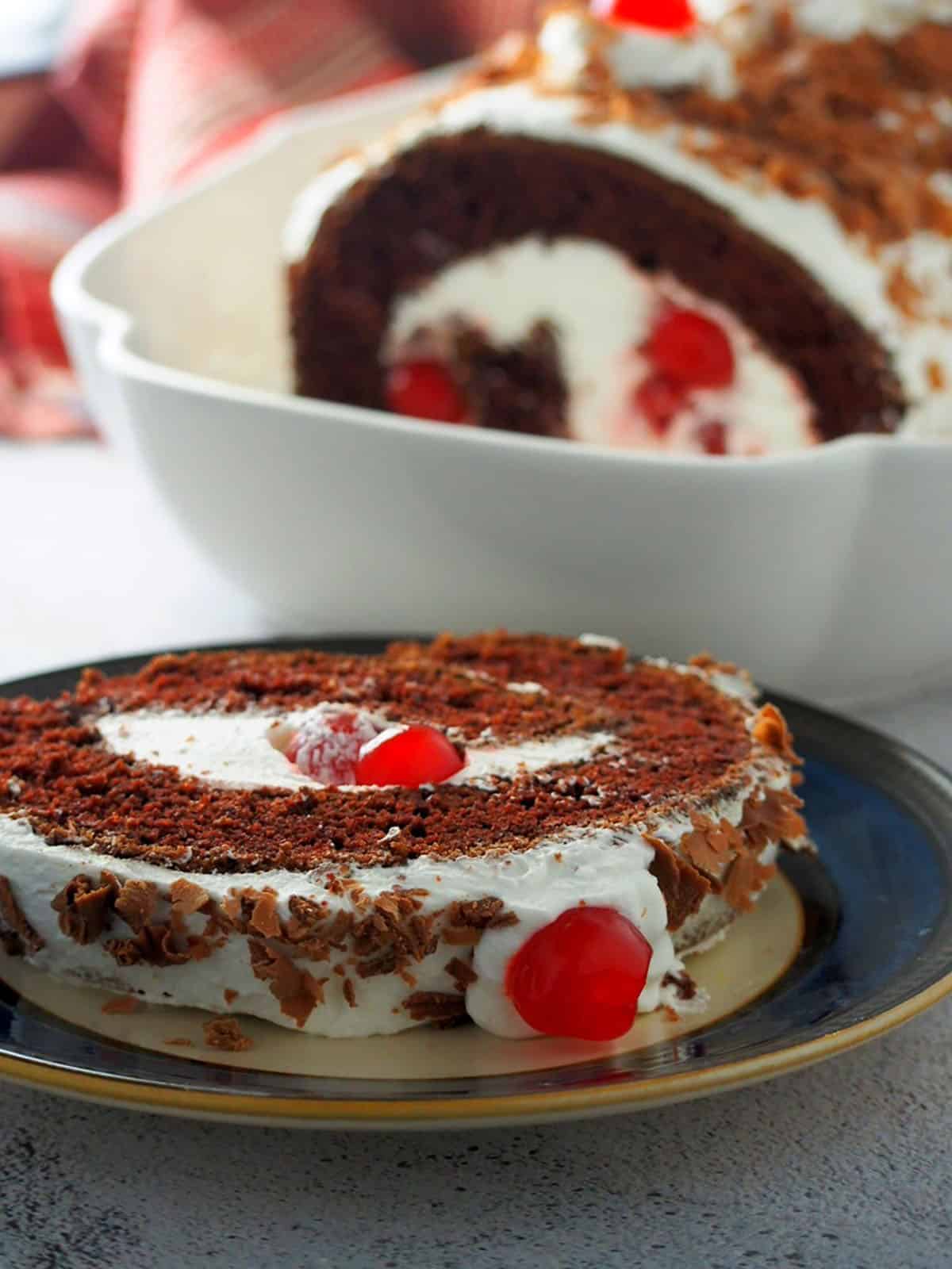 slice of black forest swiss roll cake on a serving plate.