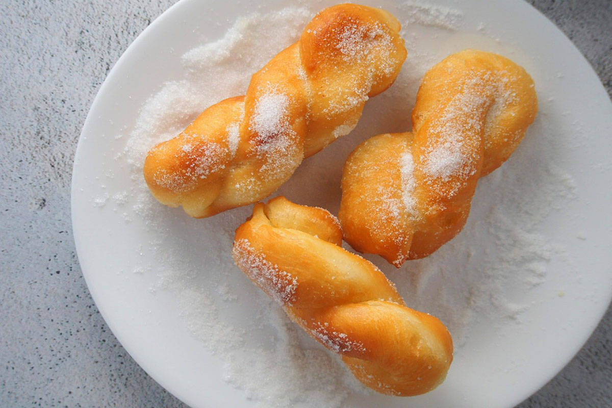 coating bicho-bicho with sugar on a white plate.