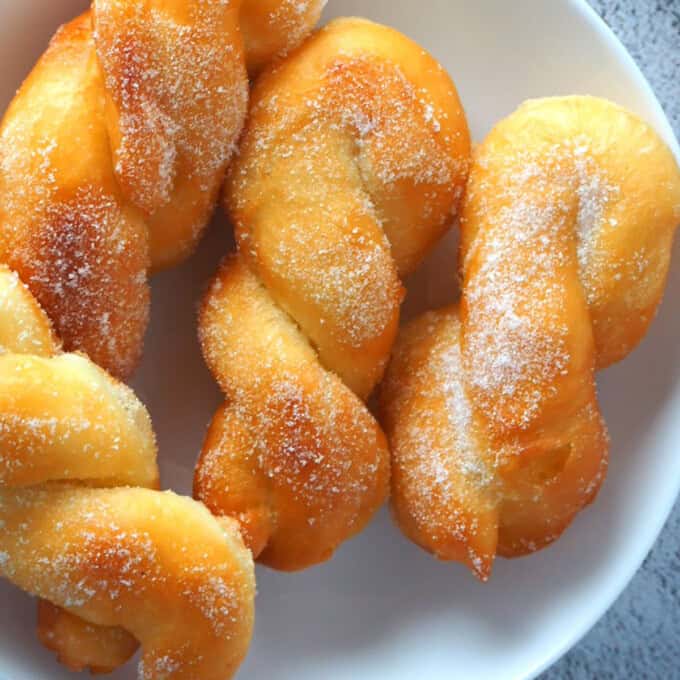 fried shakoy donuts on a white plate.