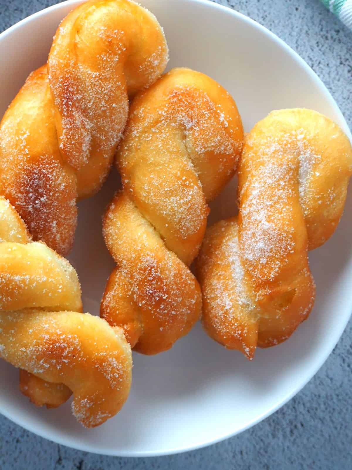 fried shakoy donuts on a white plate.