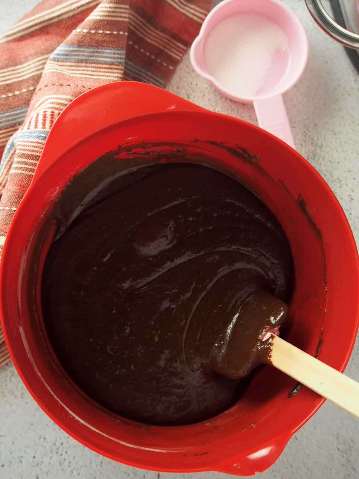 melted chocolate and cocoa powder in a red bowl with a spatula.