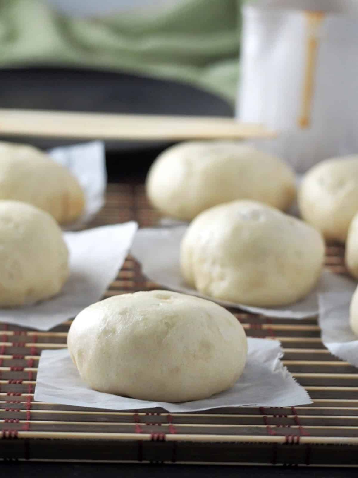 siopao buns on a bamboo placemat with siopao sauce in the background.