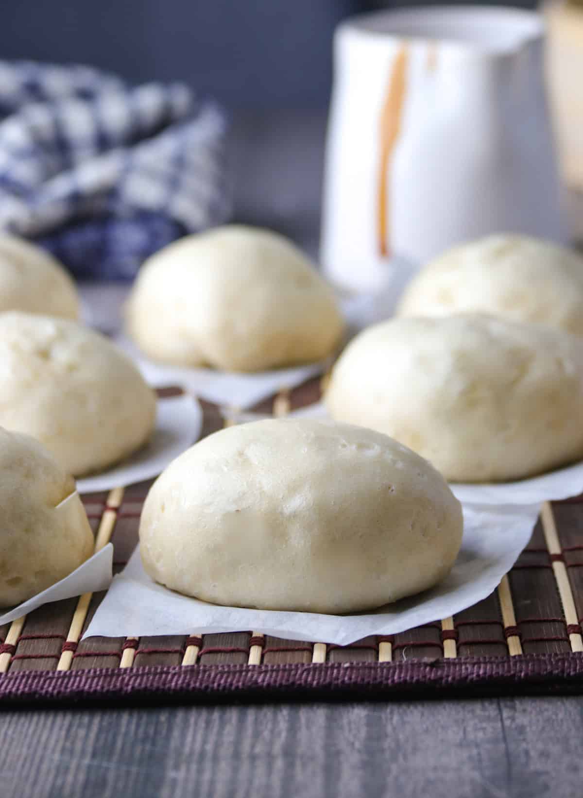 siopao buns on a bamboo placemat with siopao sauce in the background.