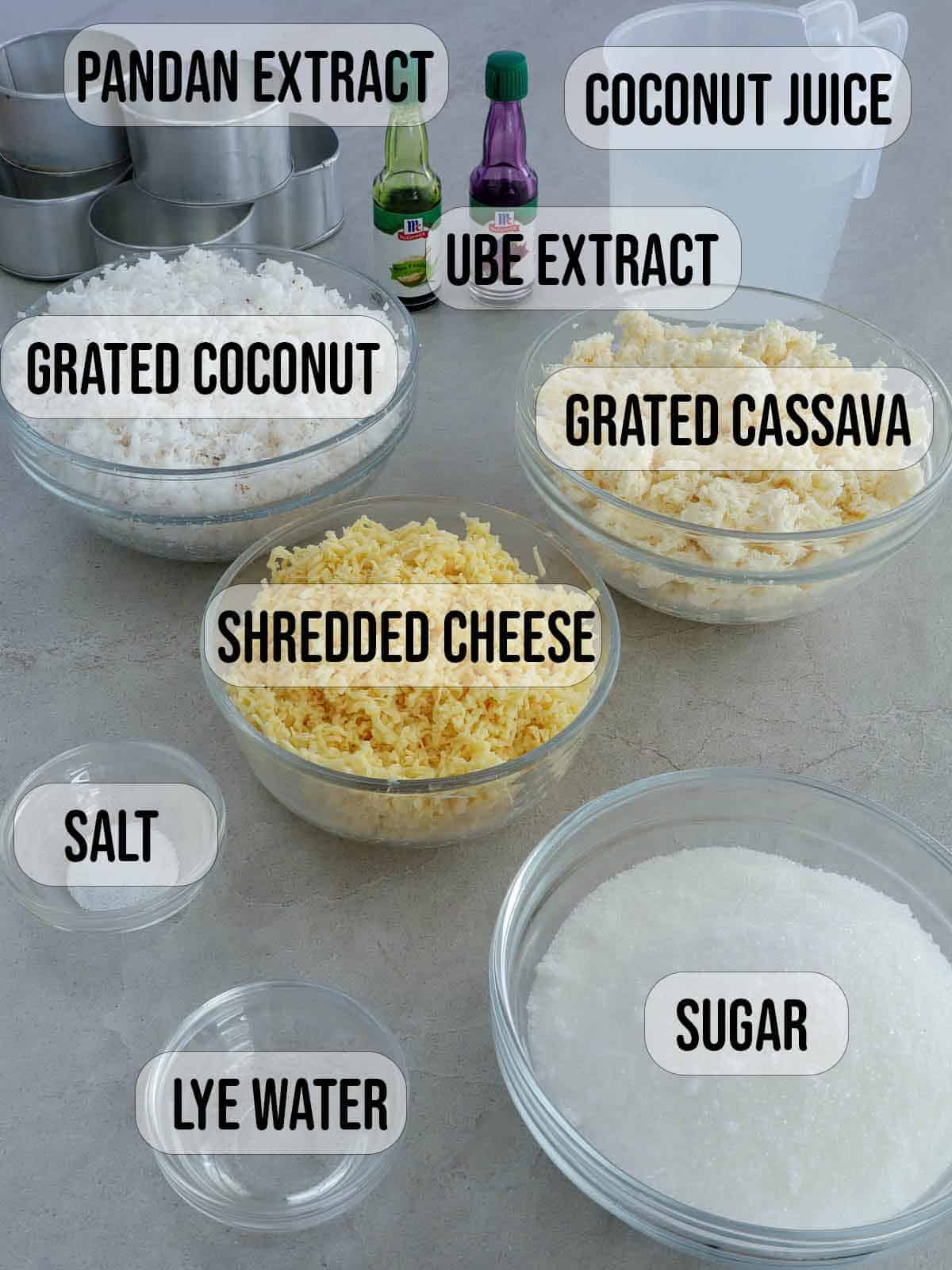 grated cassava, grated coconut, shredded cheese, salt, sugar, lye water, pandan and ube extracts, coconut juice in bowls.