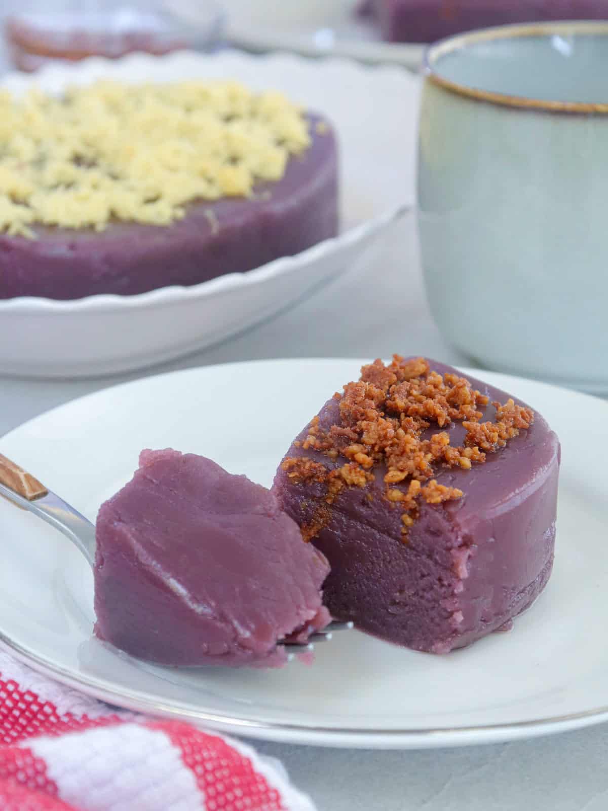slice of ube halaya with latik topping on a white serving plate.