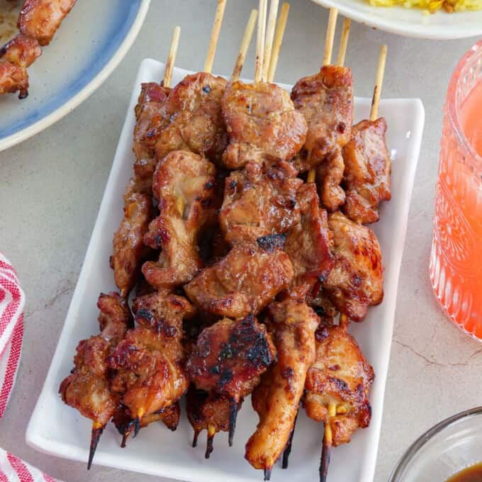 Filipino-style chicken bbq sticks on a white platter.