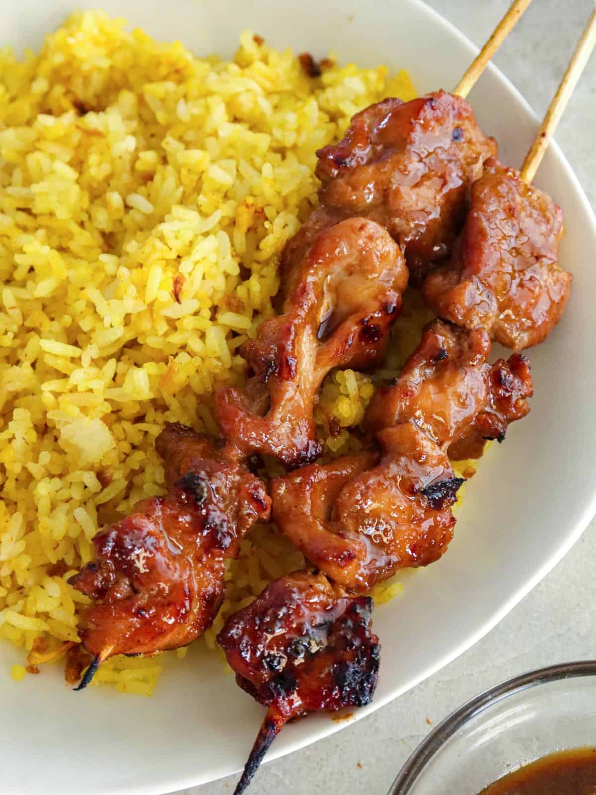 sweet mango barbecue chicken skewers on a white plate with java rice.