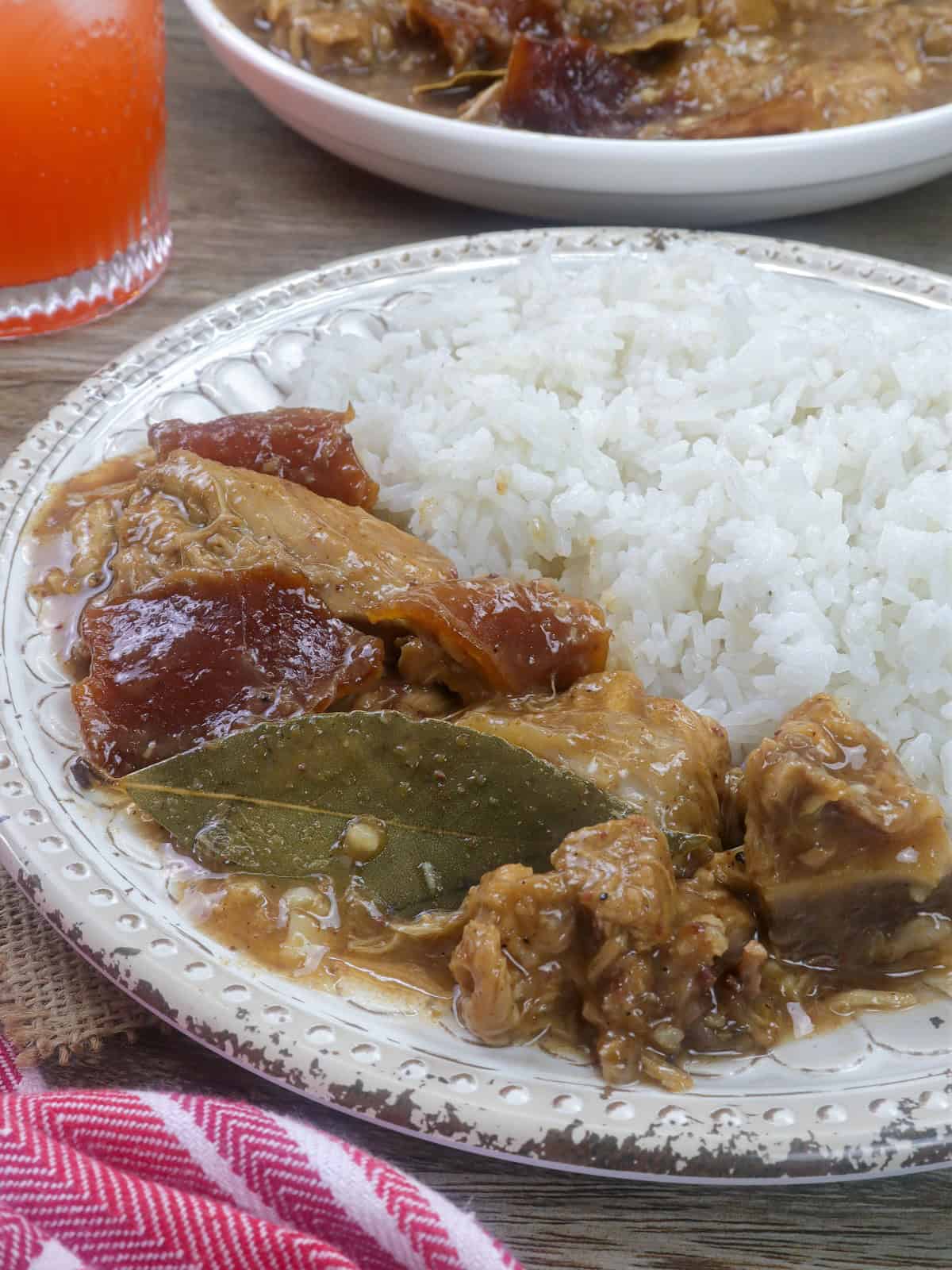 paksiw na lechon on a white plate with steamed rice.