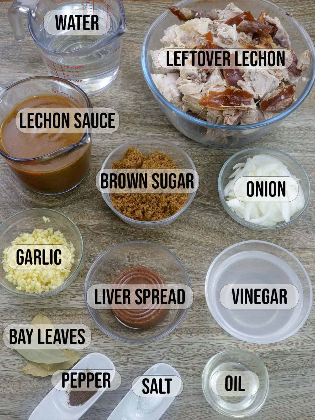 lechon sauce, liver spread, chopped roast pork, onions, vinegar, garlic, bay leaves, water, salt, pepper, brown sugar, and oil in bowls.