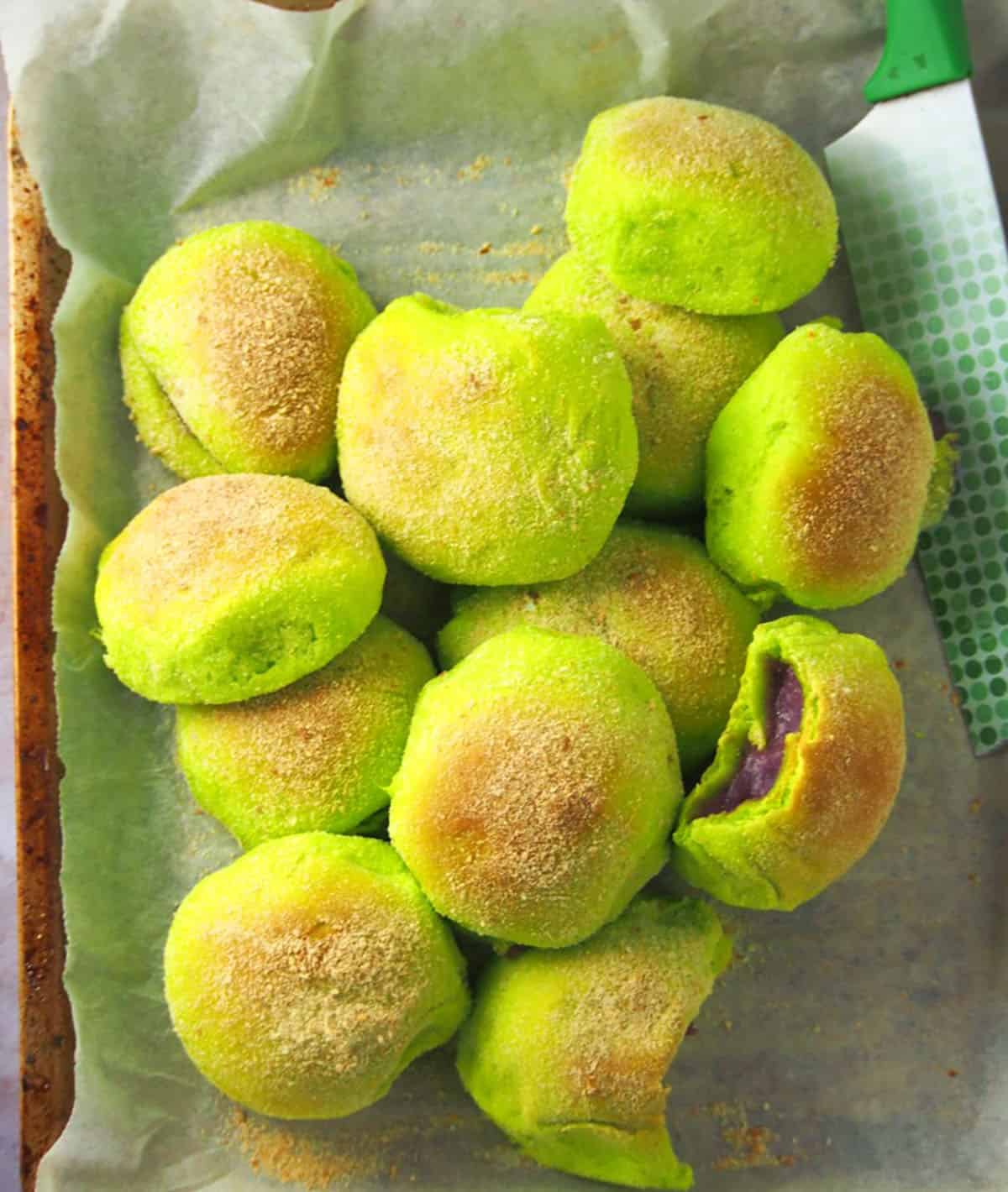 baked pandesal with pandan flavor on a parchment-lined baking sheet.