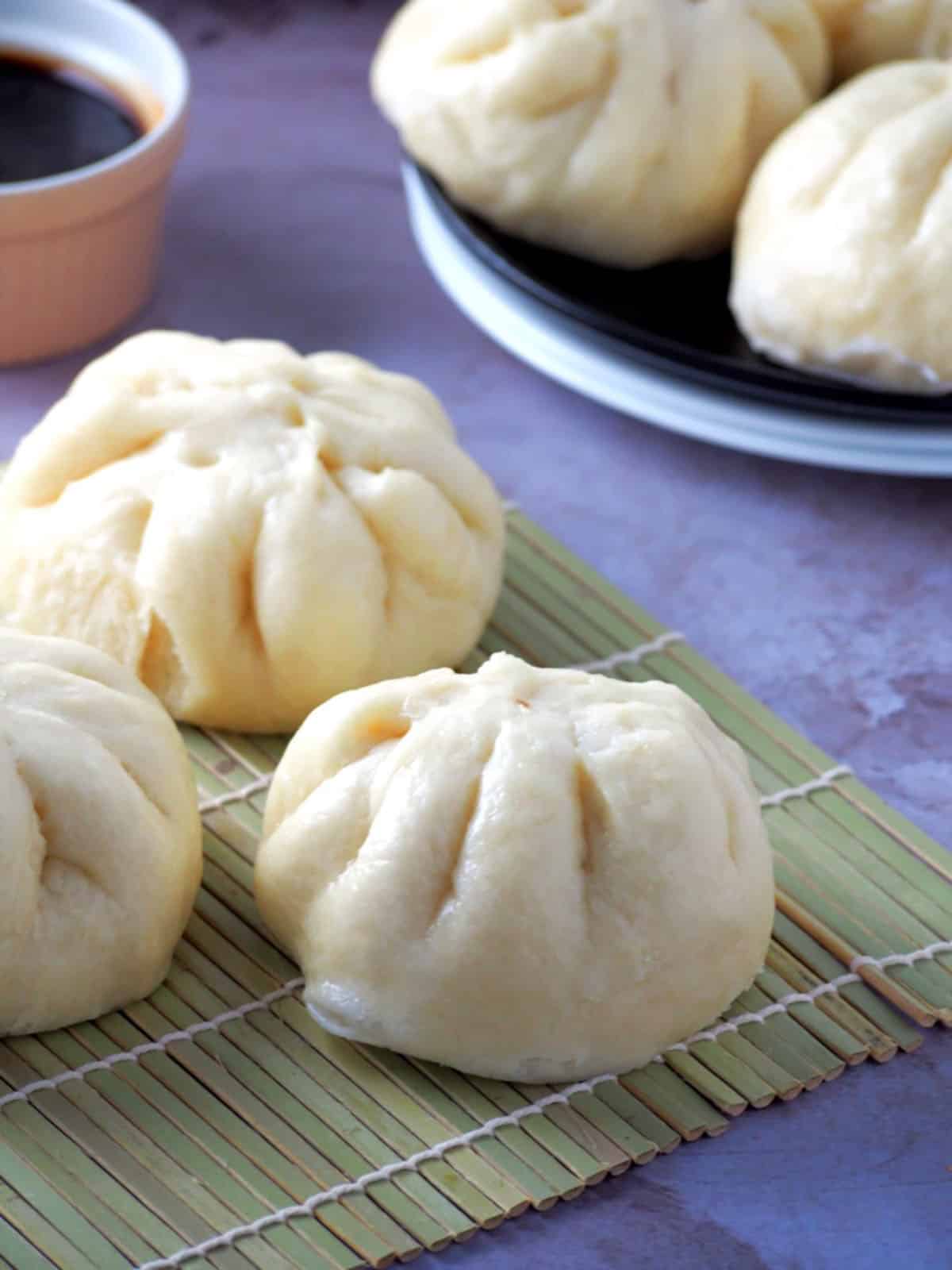 Siopao Asado buns on a bamboo mat.