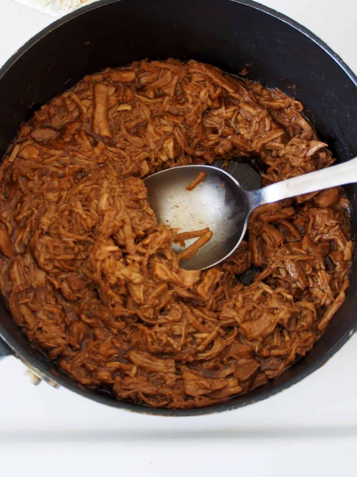 shredded pork asado cooked in a pan.