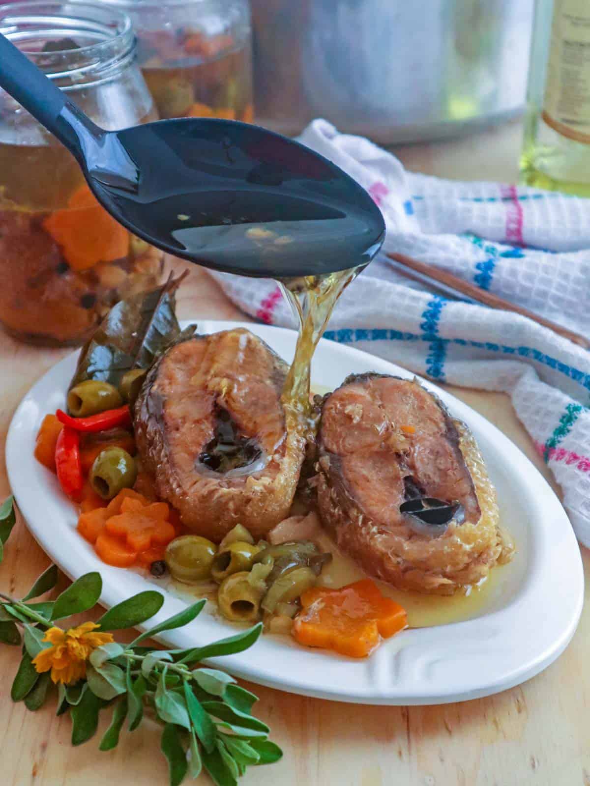 pouring olive oil over homemade sardines bangus.