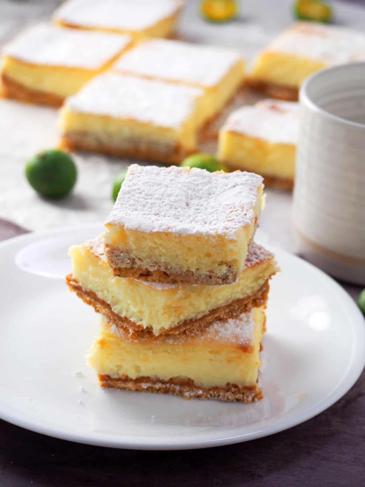 Calamansi Cheesecake Bars stacked on a white plate.