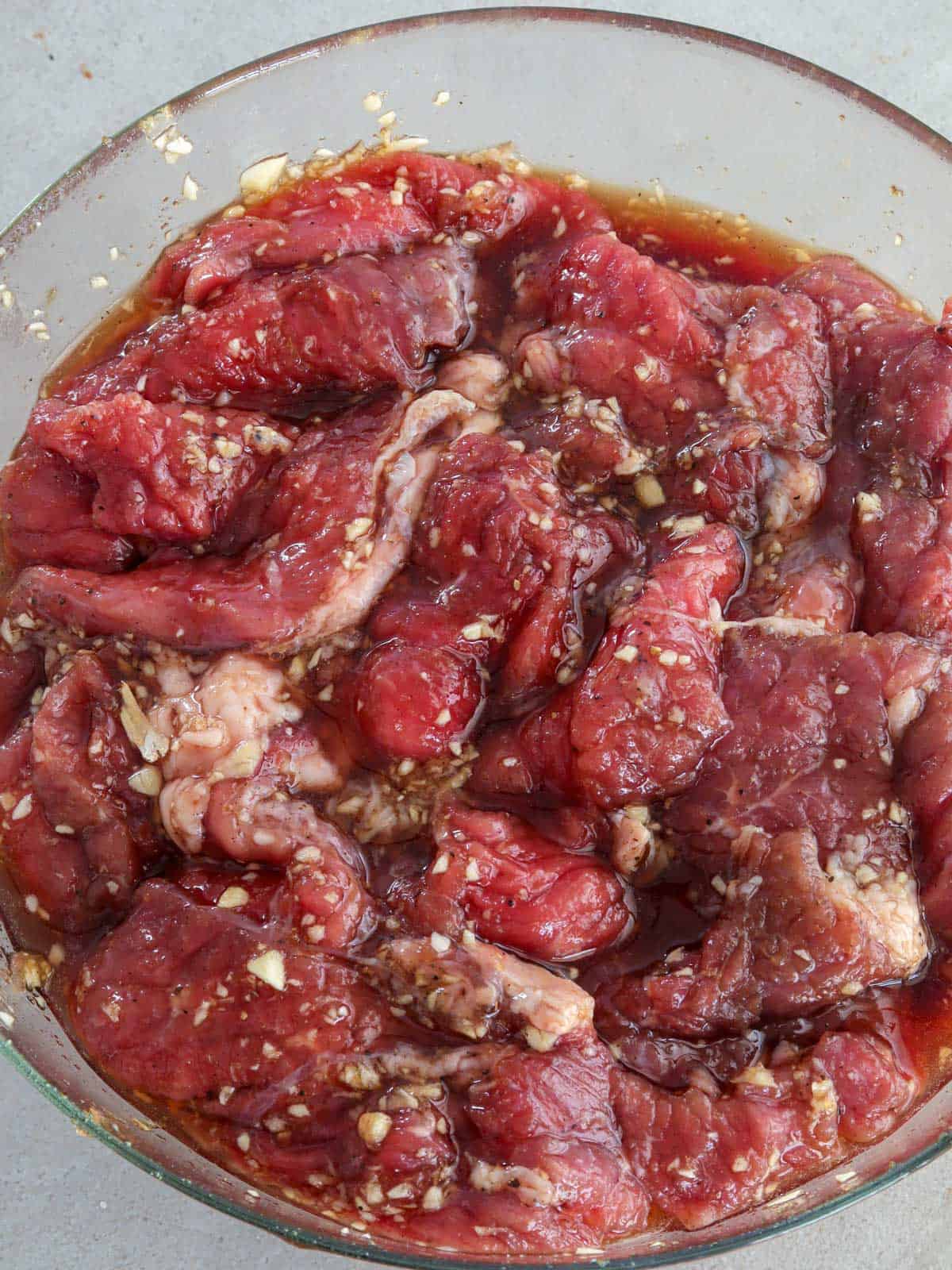 marinating tapa damulag in a glass bowl.