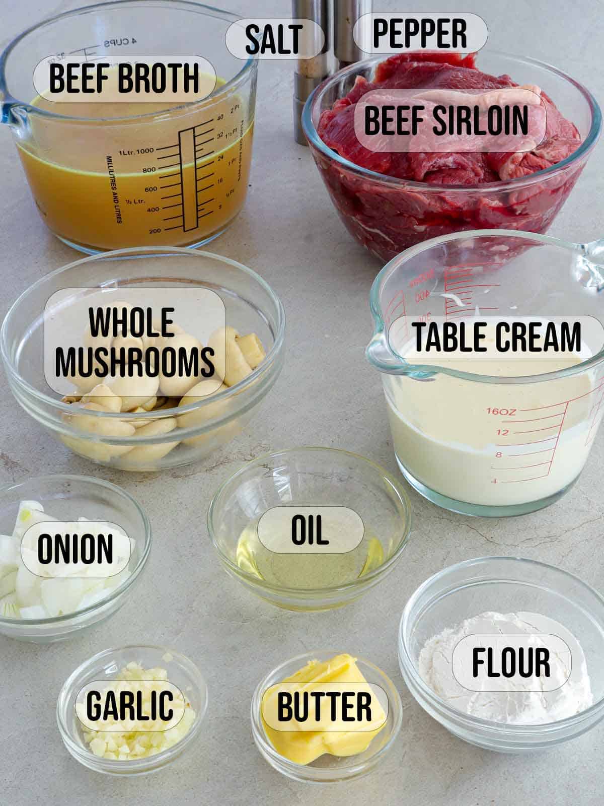 sliced beef, button mushrooms, minced garlic, onions, table cream, oil, butter, broth in bowls.