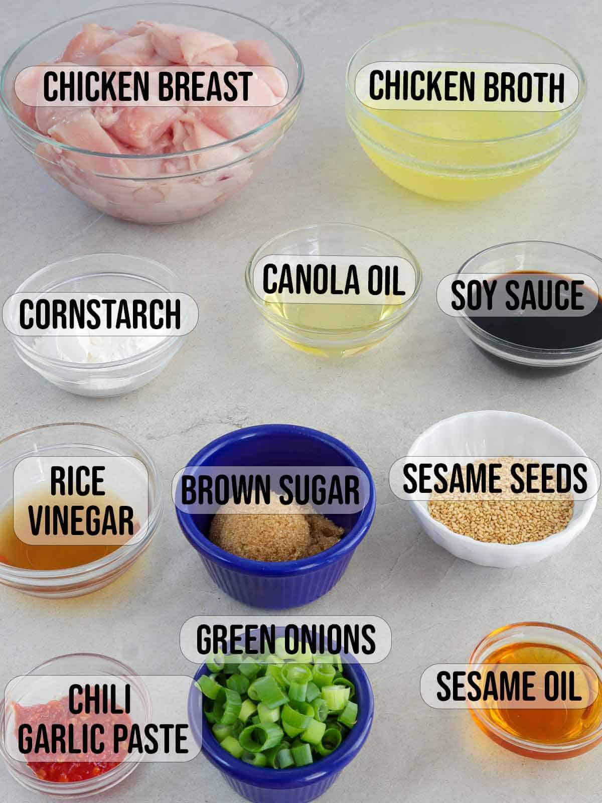 chicken breast, rice vinegar, oil soy sauce, broth, brown sugar, sesame oil, sesame seeds, green onions, chili garlic paste in bowls.
