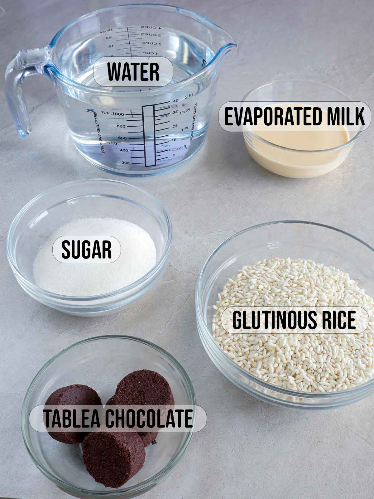 glutinous rice, tablea, sugar, milk, water in bowls.
