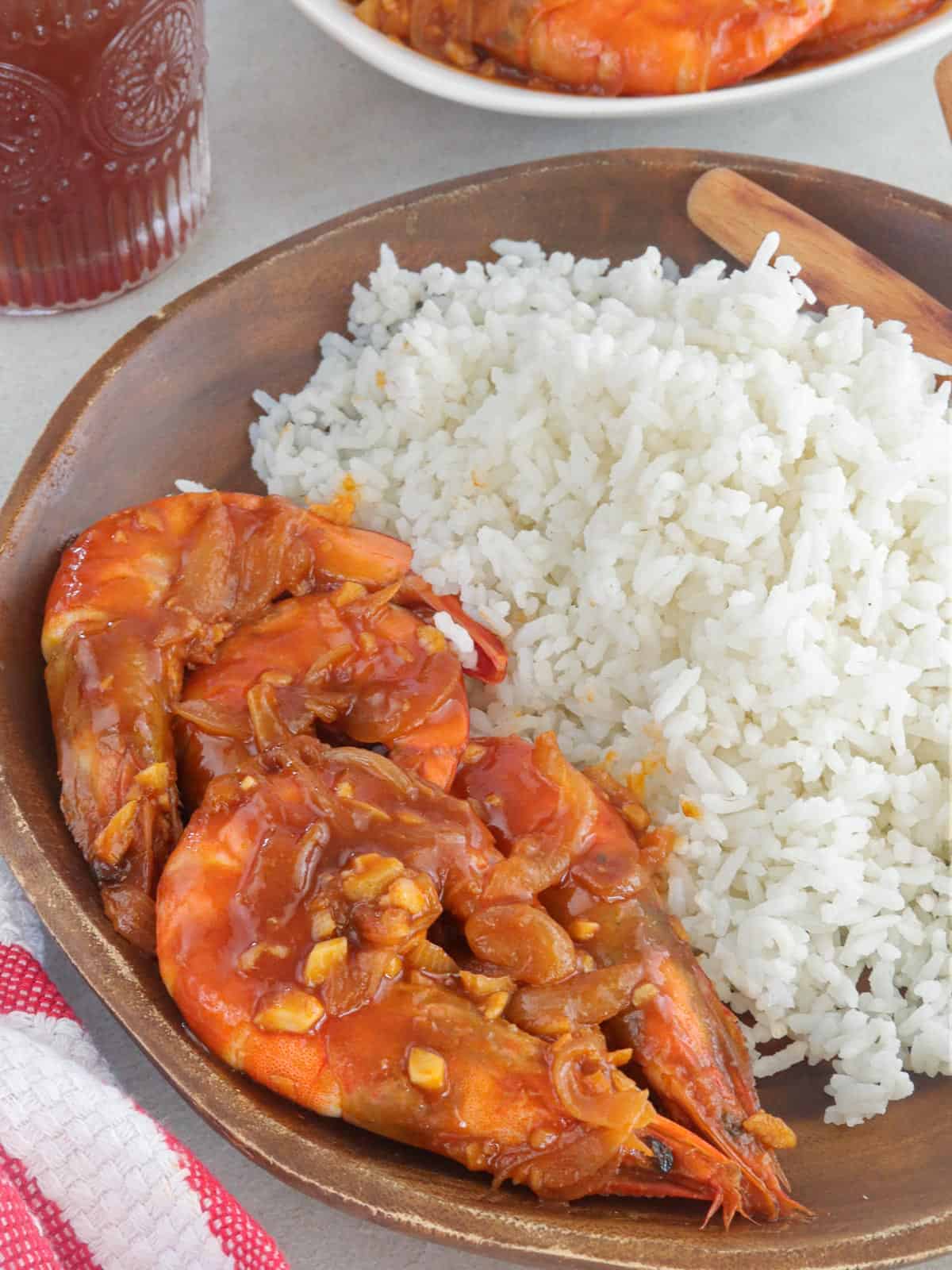 Shrimp with Oyster Sauce on a wooden plate with steamed rice on the side.