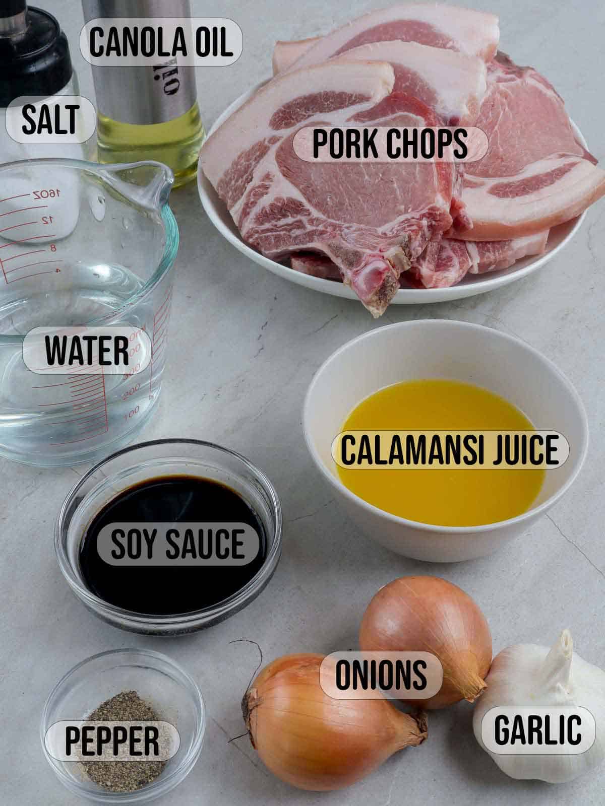 pork chops, calamansi juice, water, soy sauce, onions, garlic, oil, salt, pepper in bowls.