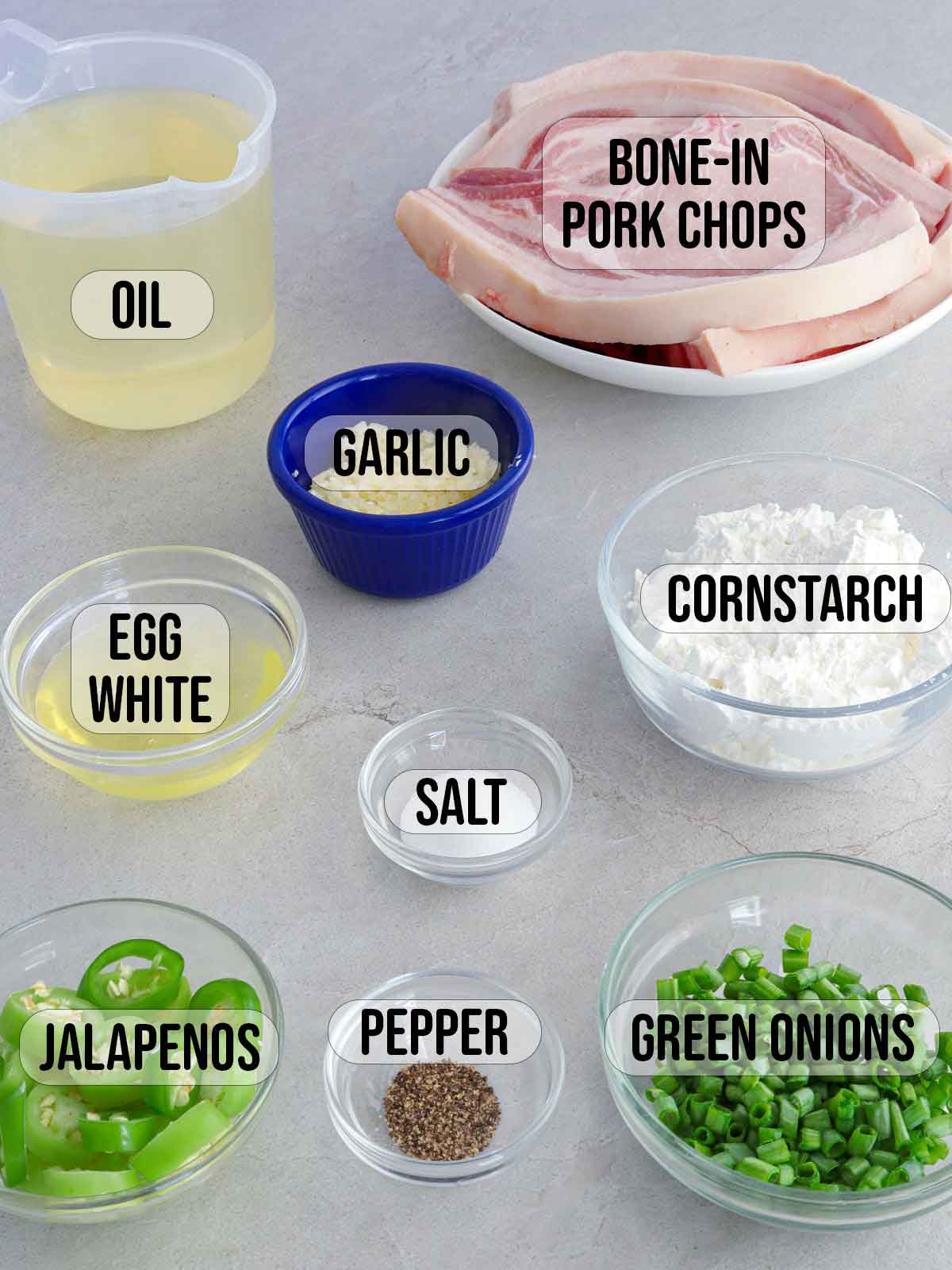 pork chops, cornstarch, jalapenos, oil, salt, pepper, egg whites, garlic, jalapenos, green onions in bowls.